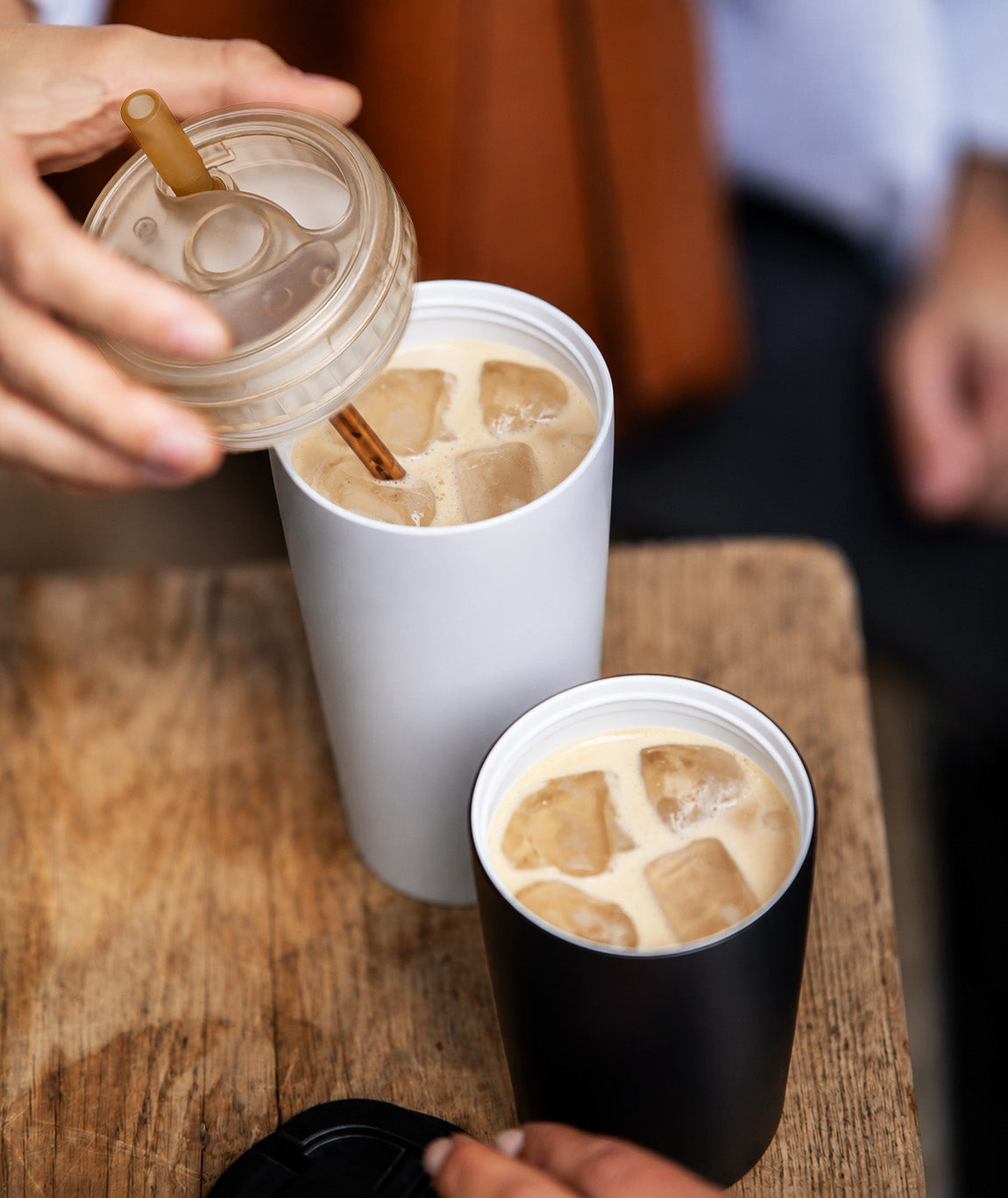 Iced coffee poured over large ice cubes in a black Kisskind cup