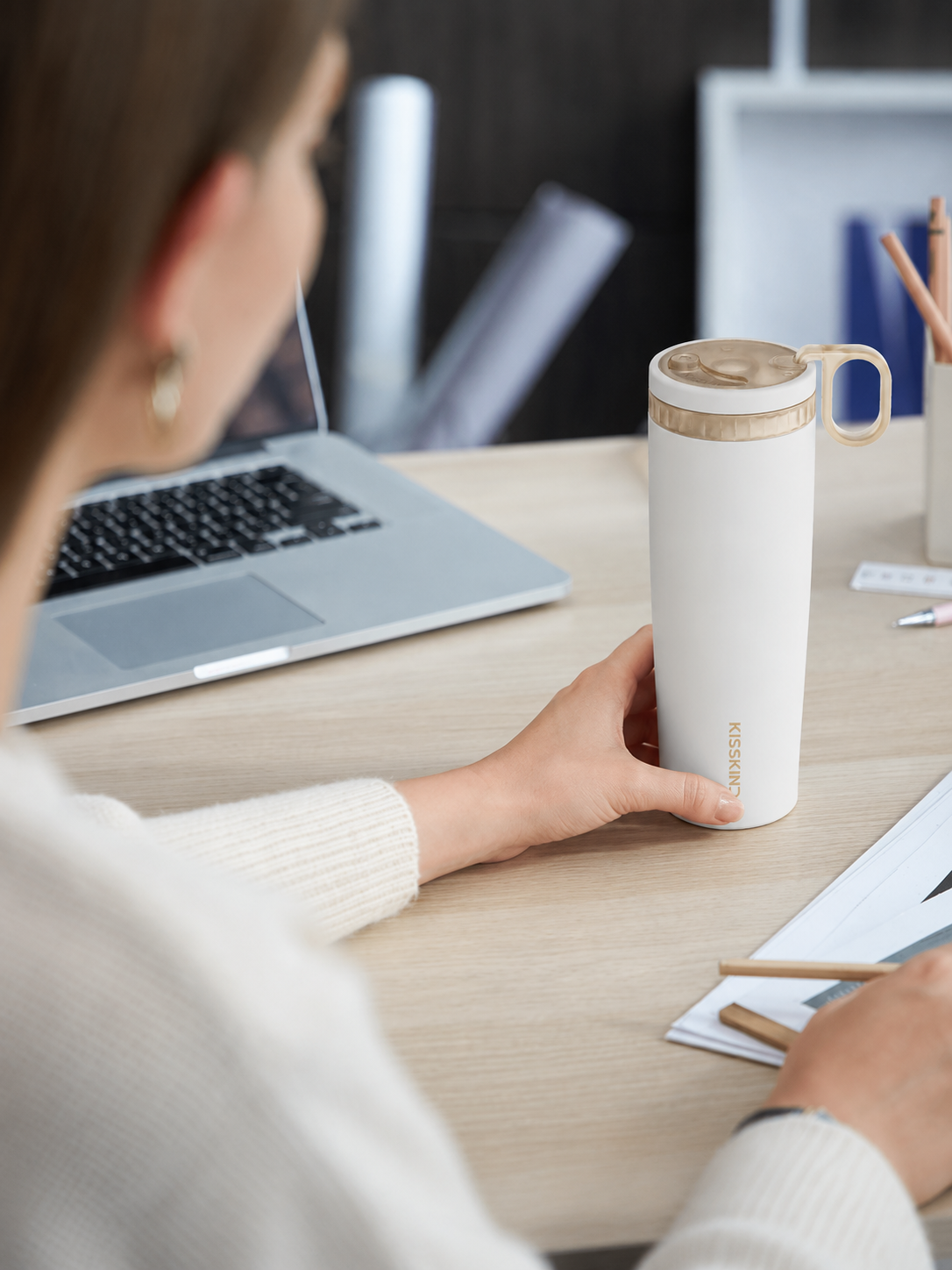 White Kisskind cup beside a laptop in a naturally lit workday setting