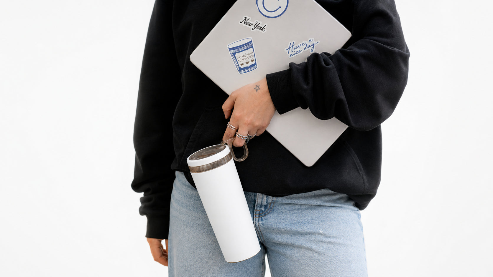 Carrying a laptop in one arm, with the white cup hooked on one finger by its ring