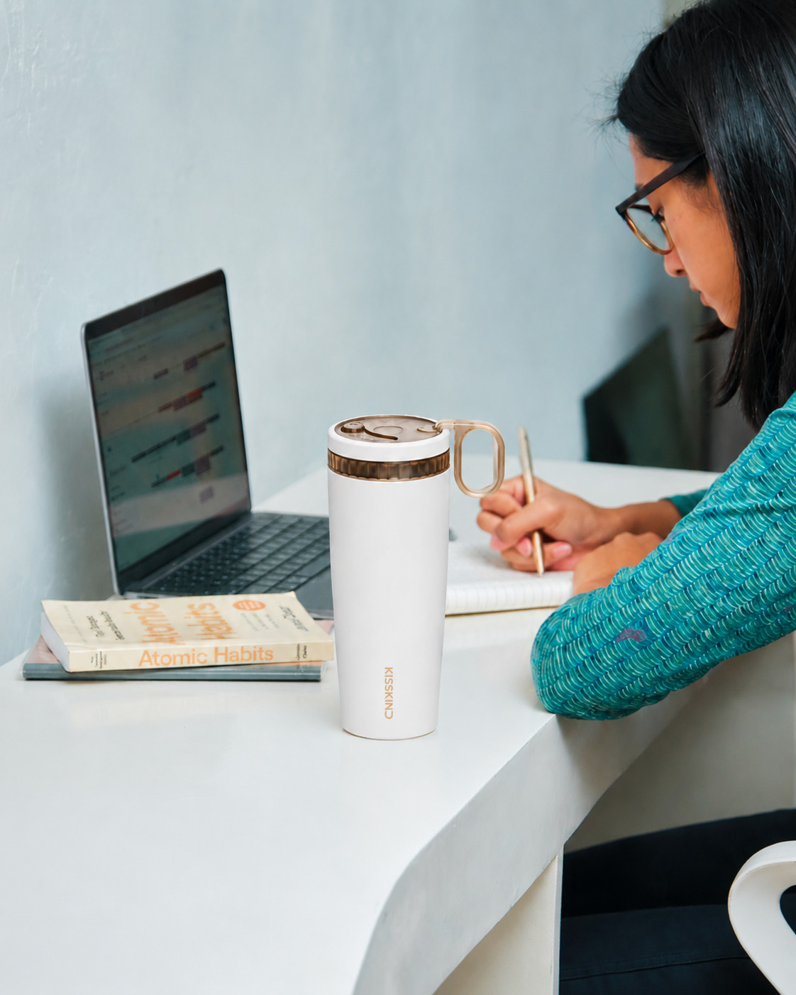KissKind cup beside a laptop on a desk