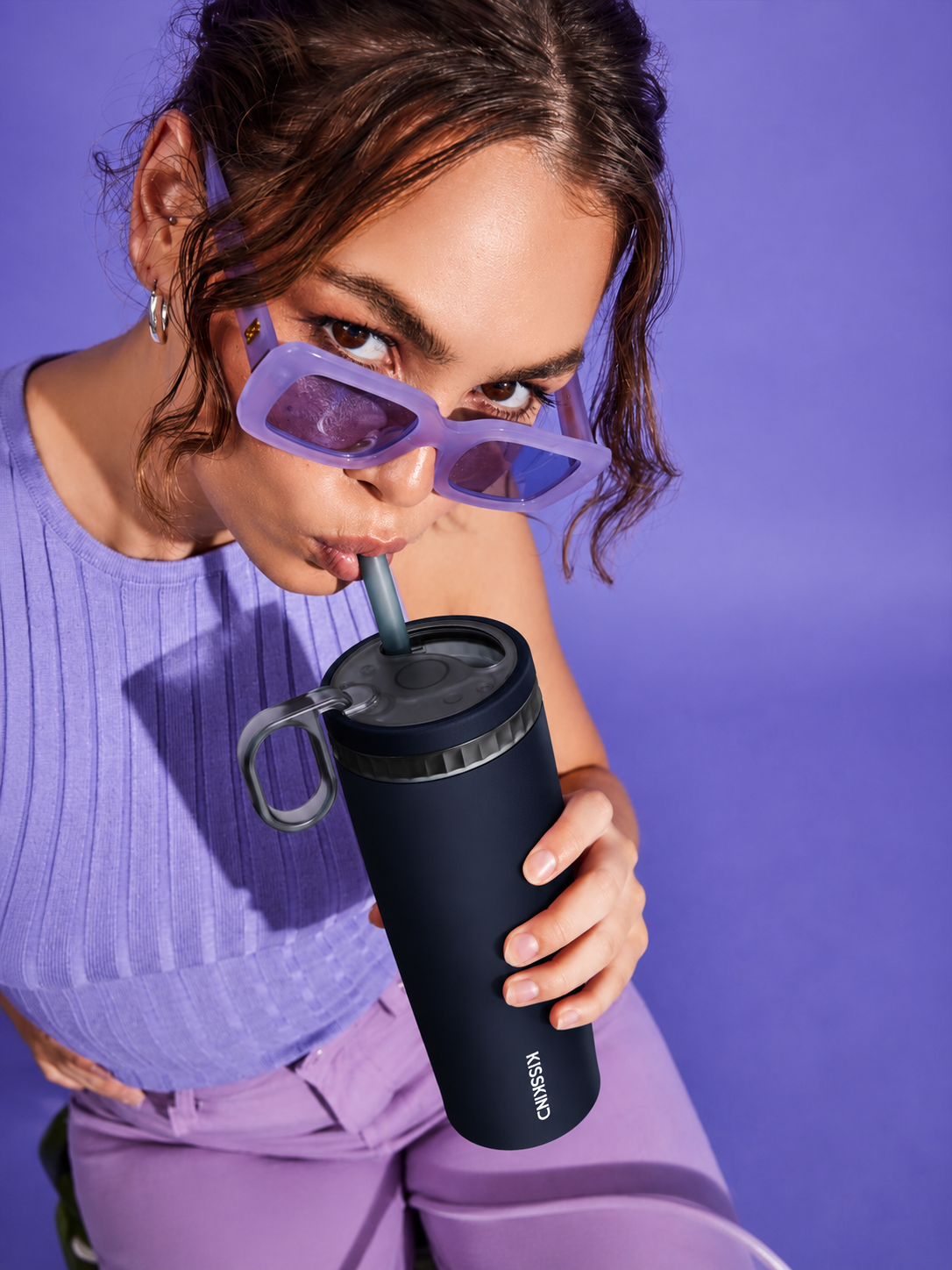 Person drinking from a black KissKind cup